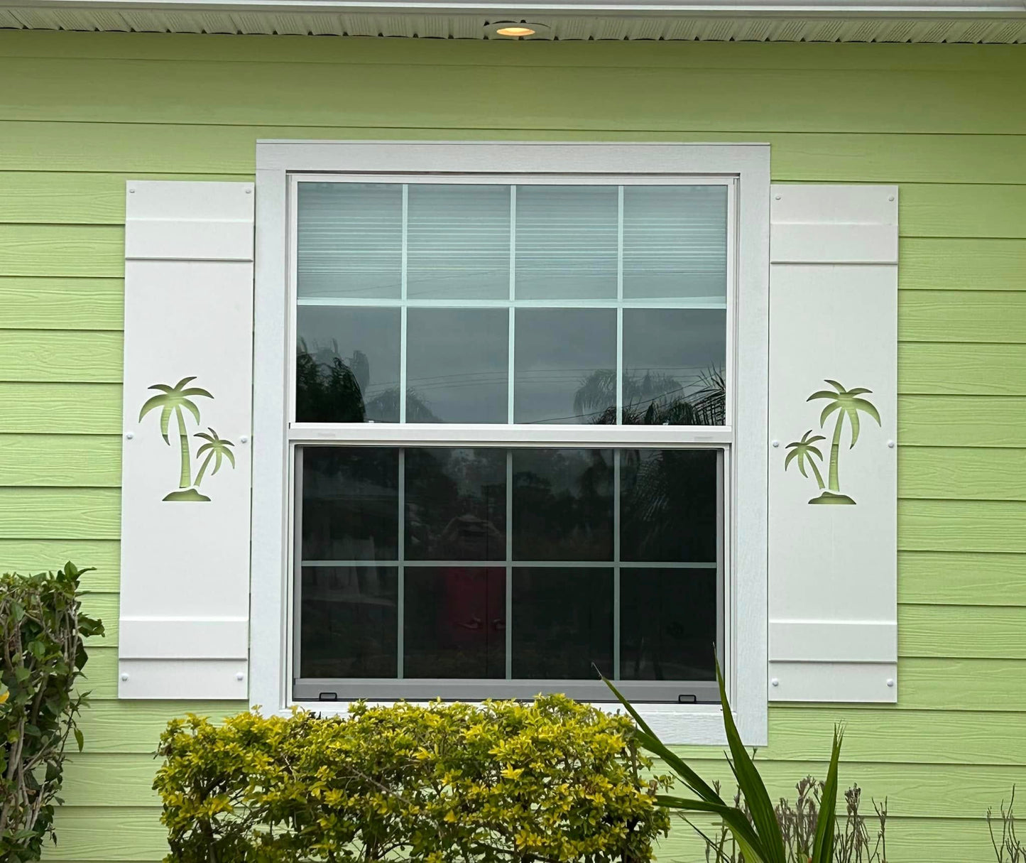 Window with white shutters on a green house exterior