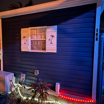 Outdoor setting with a dark blue wall, palm tree decorations, and a small table with items.