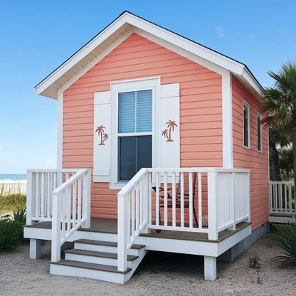 Small pink beach house with a white deck and palm tree decorations on a clear day.